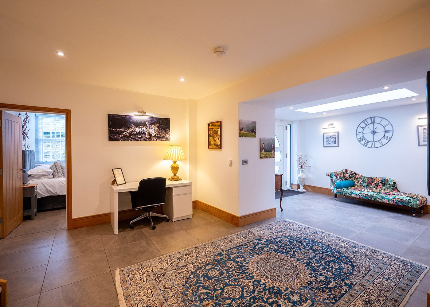 A living room with a desk , chair , rug and couch.