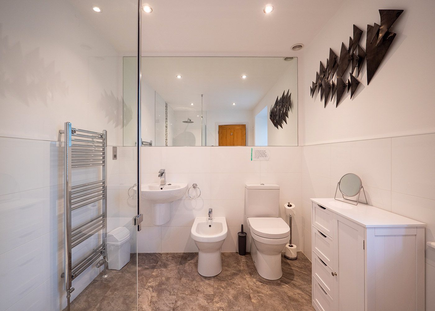 A bathroom with a toilet , sink , bidet and walk in shower.