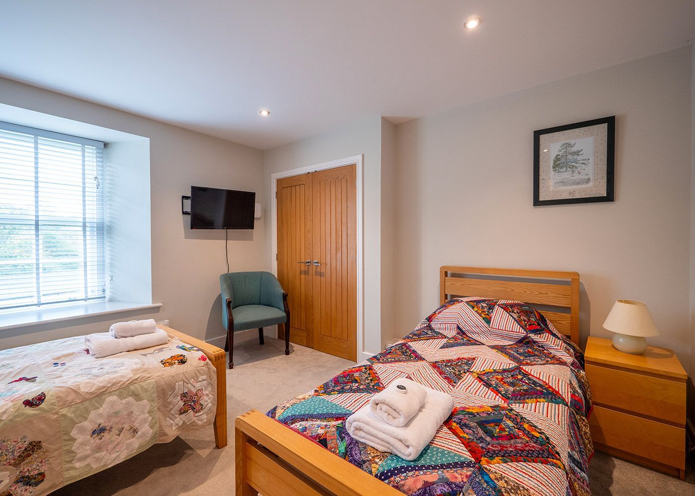 A bedroom with two beds , a chair , a television and a window.