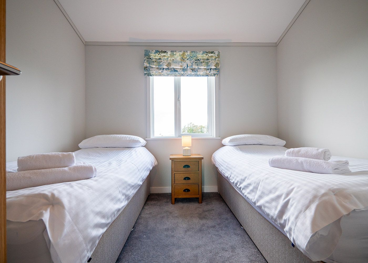A bedroom with two twin beds and a nightstand.