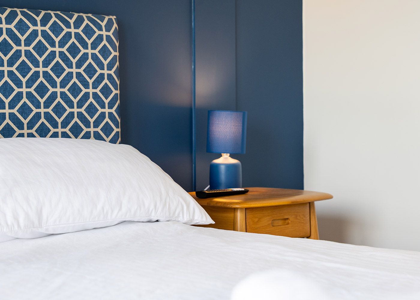 A bed with a blue headboard and a blue lamp on a nightstand.
