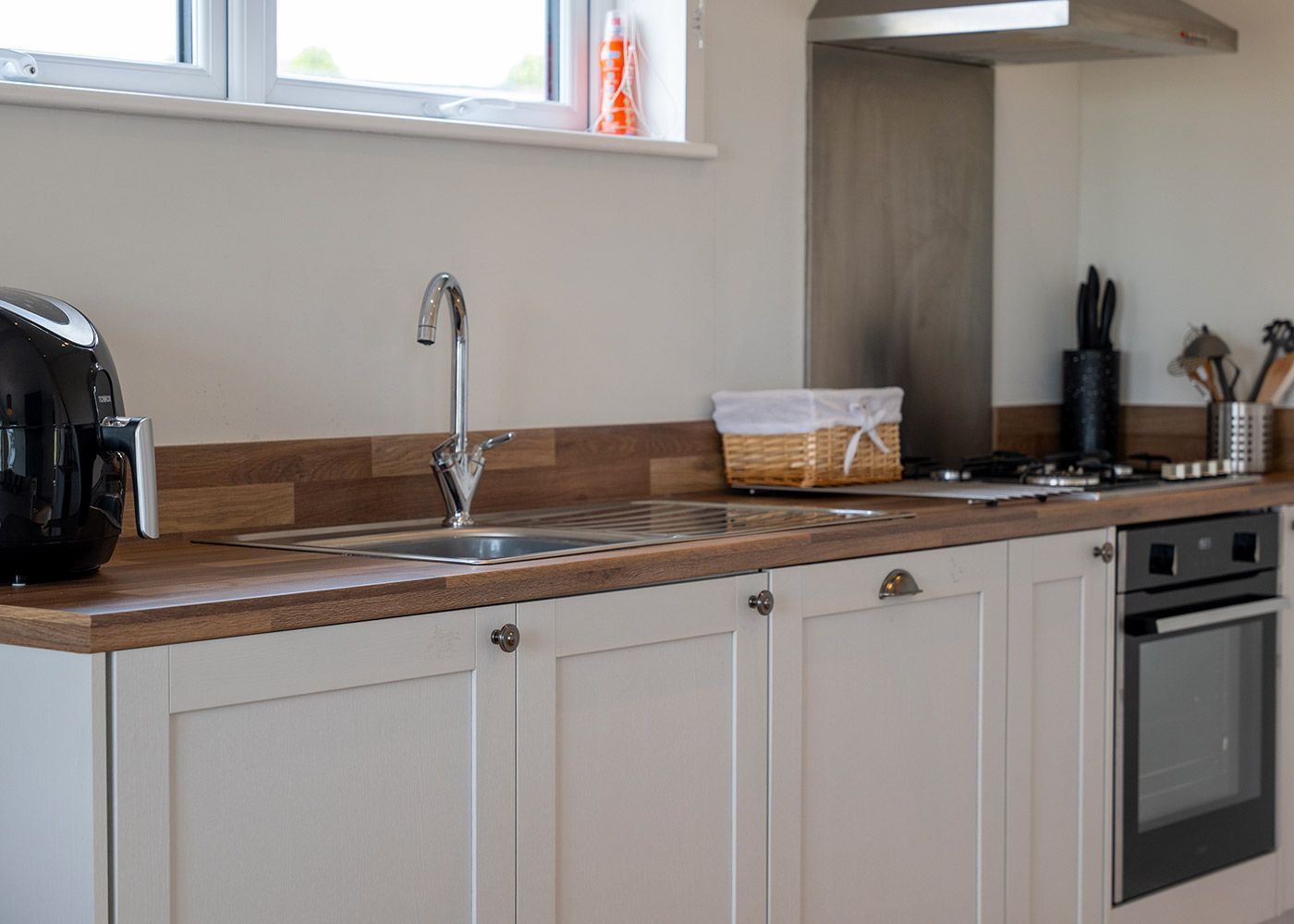 A kitchen with white cabinets , a sink , an oven , and a toaster oven.