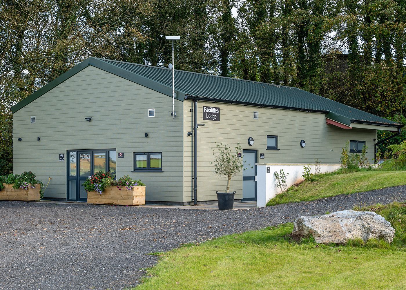 A house with a green roof is sitting on top of a grassy hill.