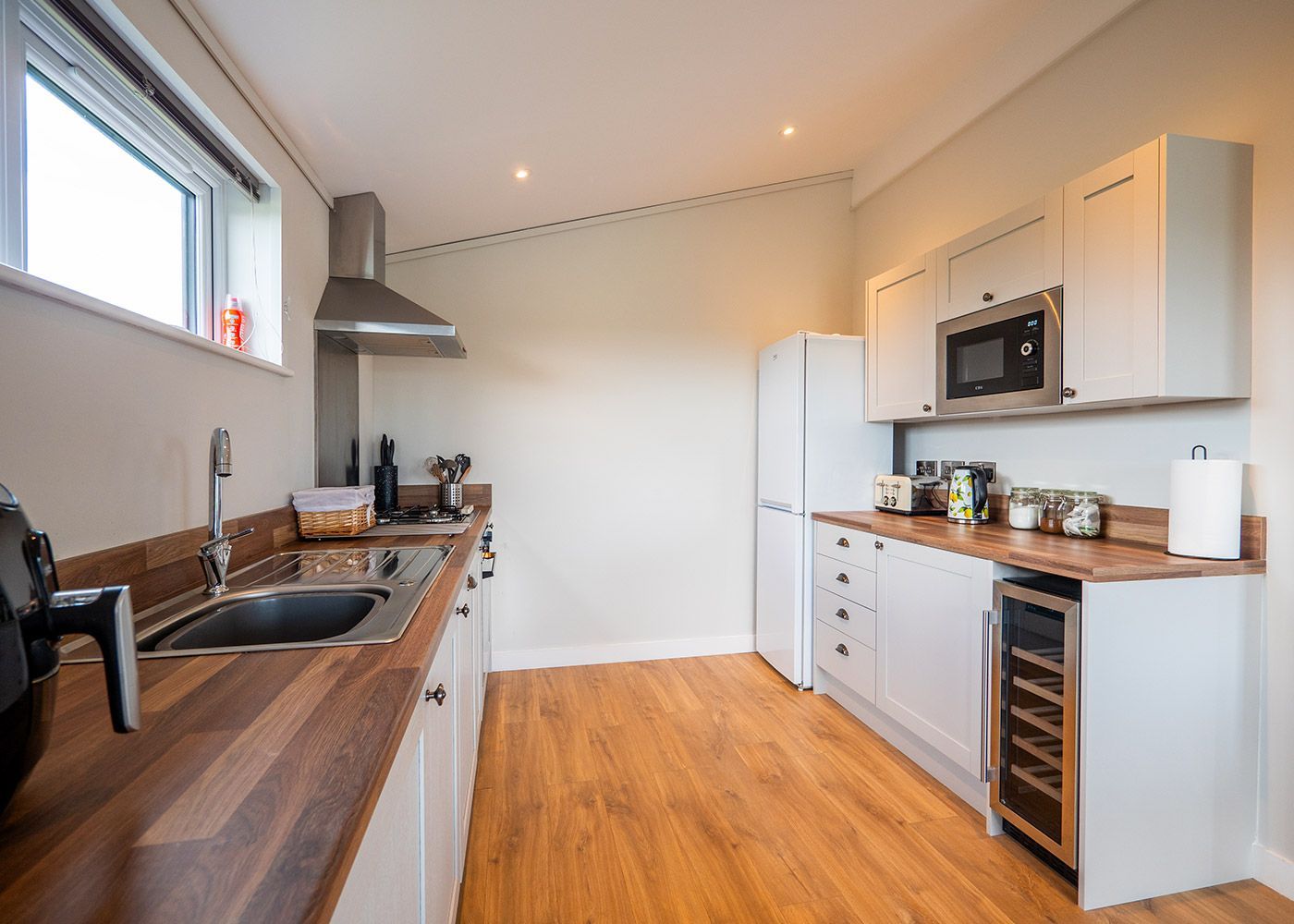 A kitchen with a sink , refrigerator , microwave , and wine cooler.
