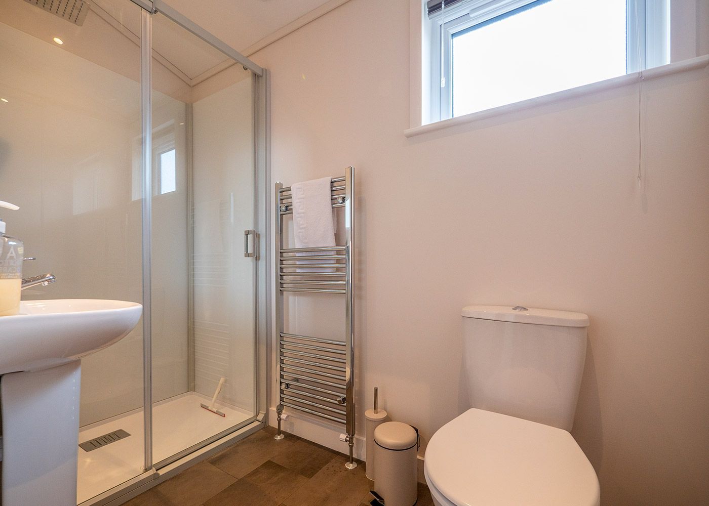 A bathroom with a toilet , sink and shower.