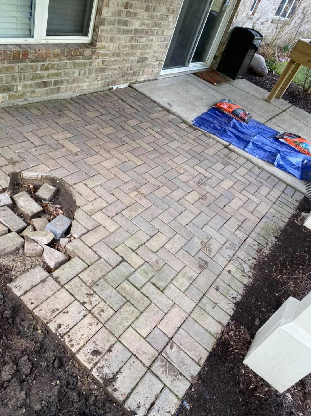 A brick patio is being built in front of a brick house.