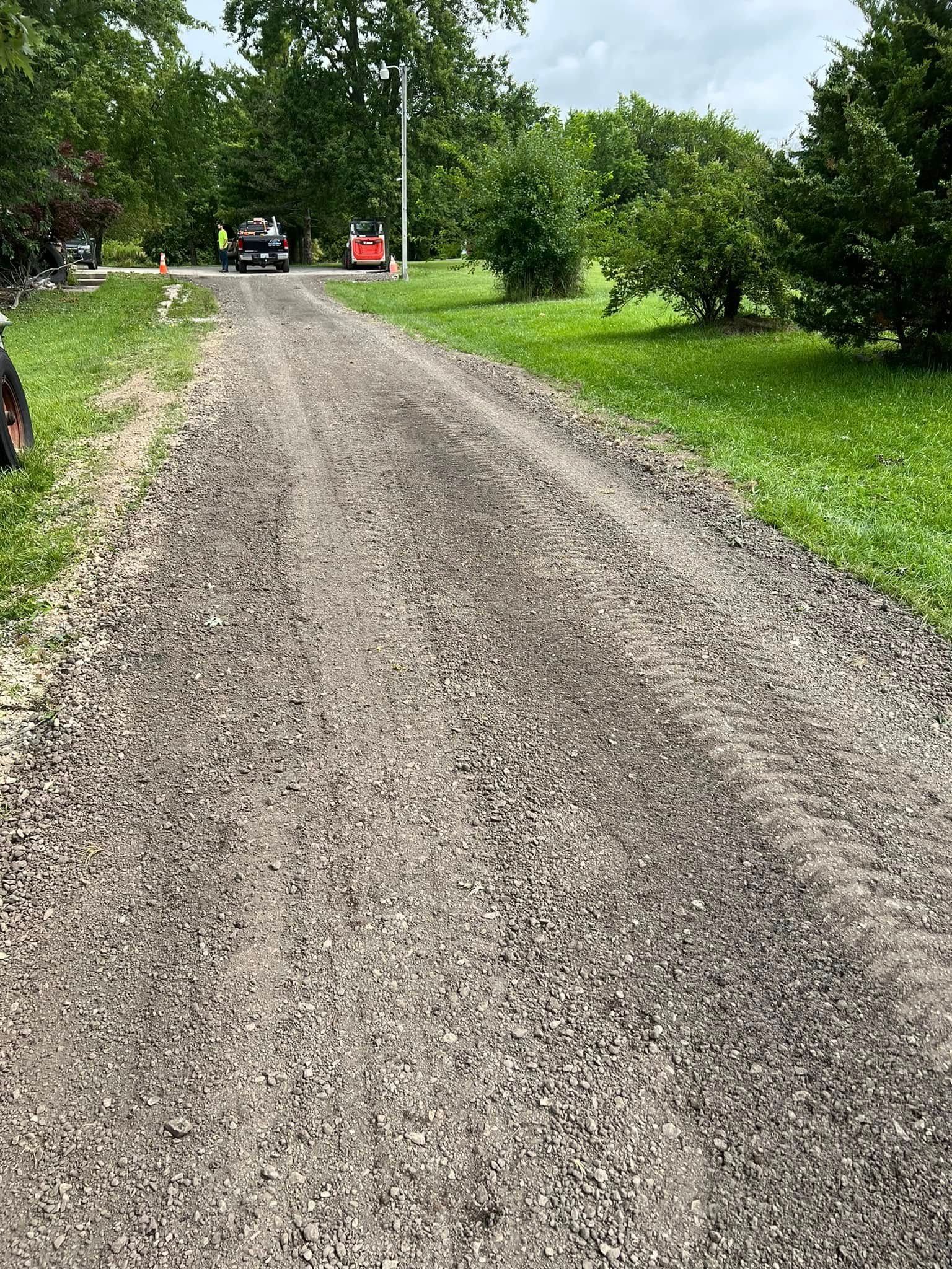 A gravel road going through a grassy field.