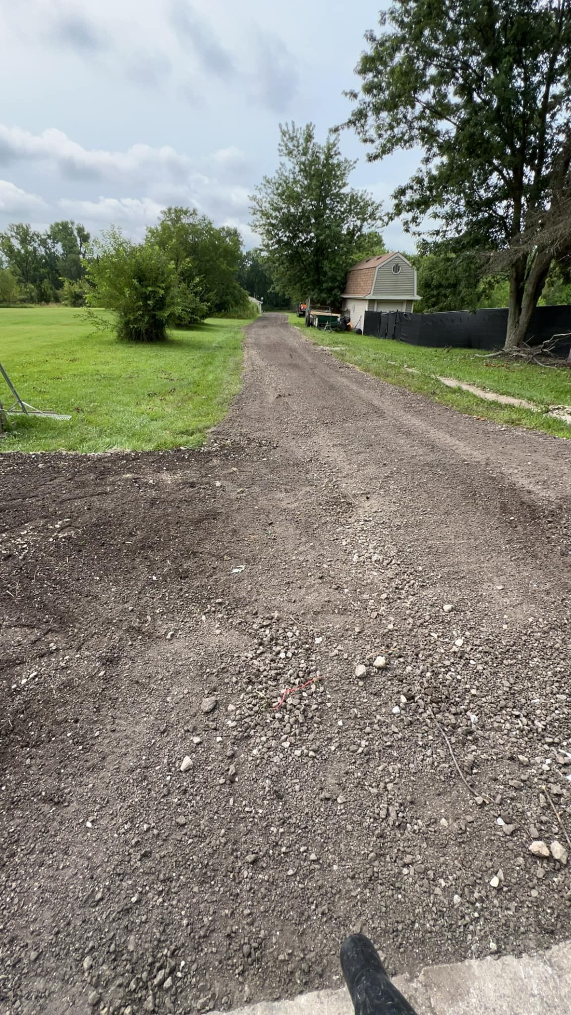 A gravel road going through a grassy field.