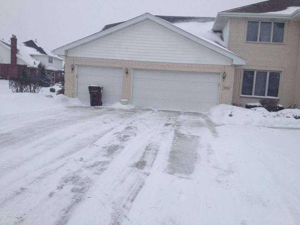 A snowy driveway in front of a house