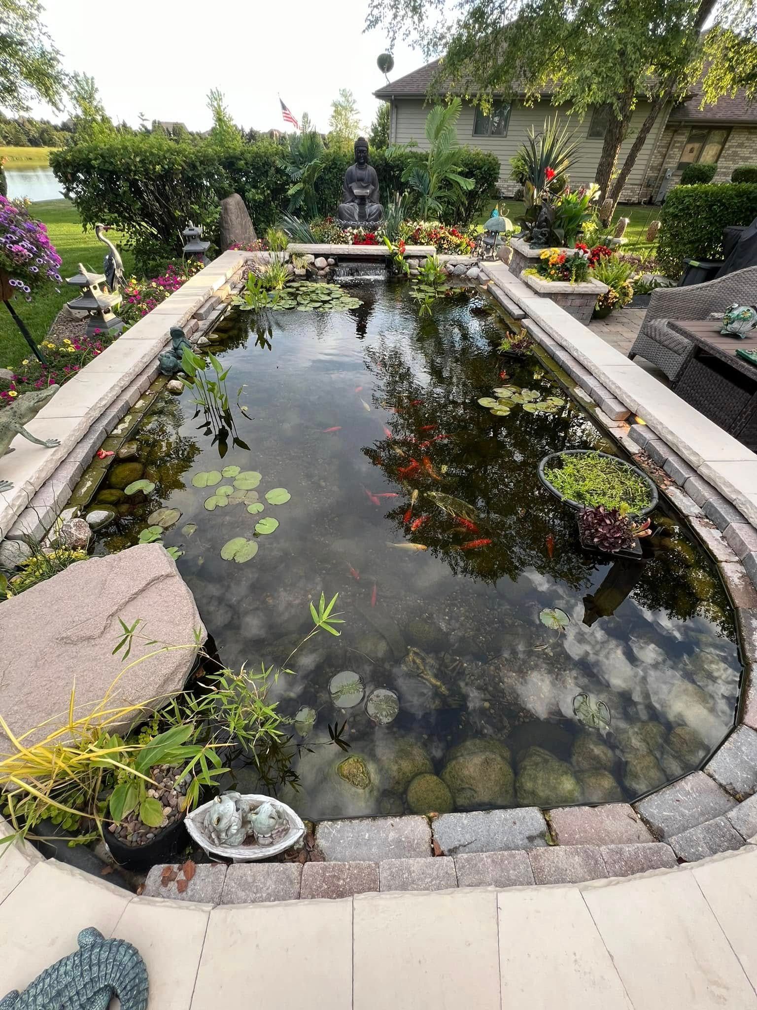 A large pond filled with water lilies and rocks in a garden.