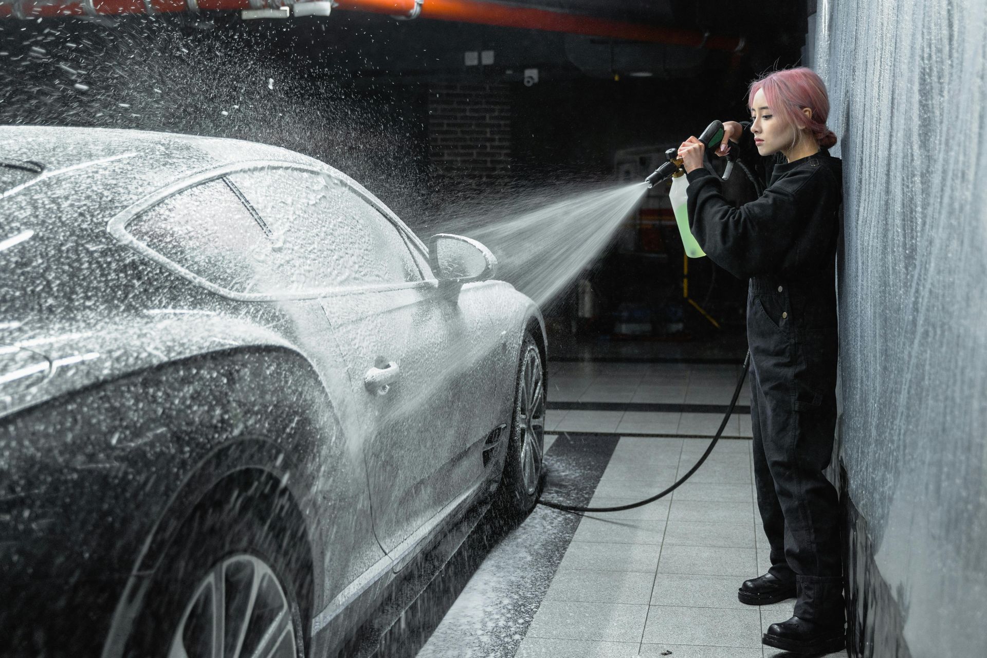A person is using a high pressure washer to clean a brick walkway.
