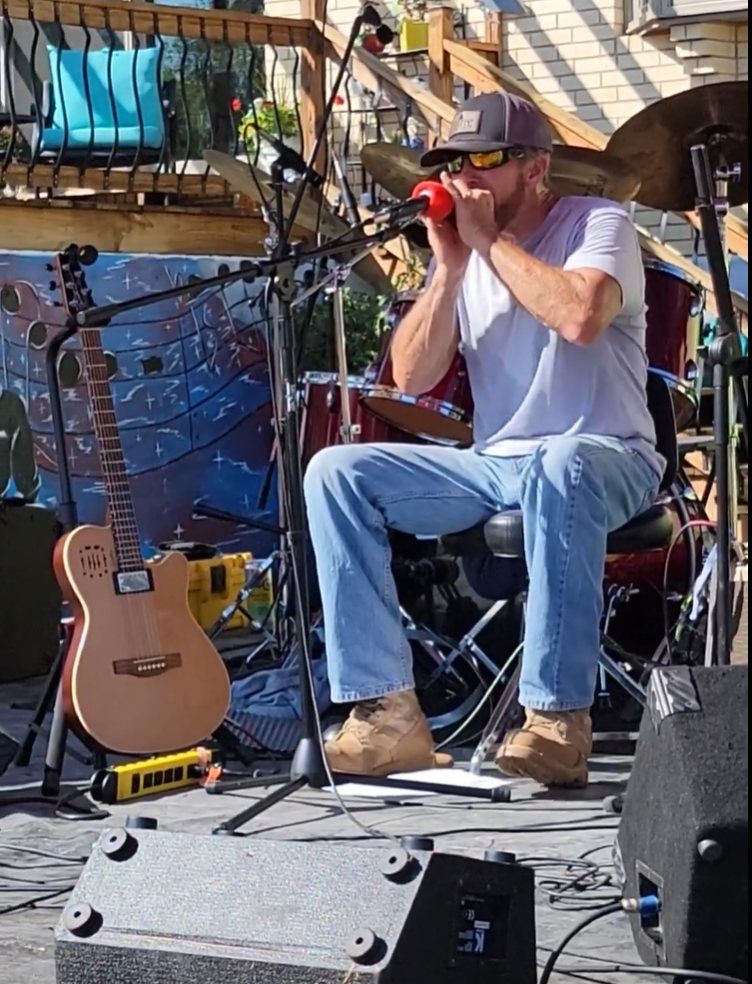 A man is sitting on a stage playing a harmonica
