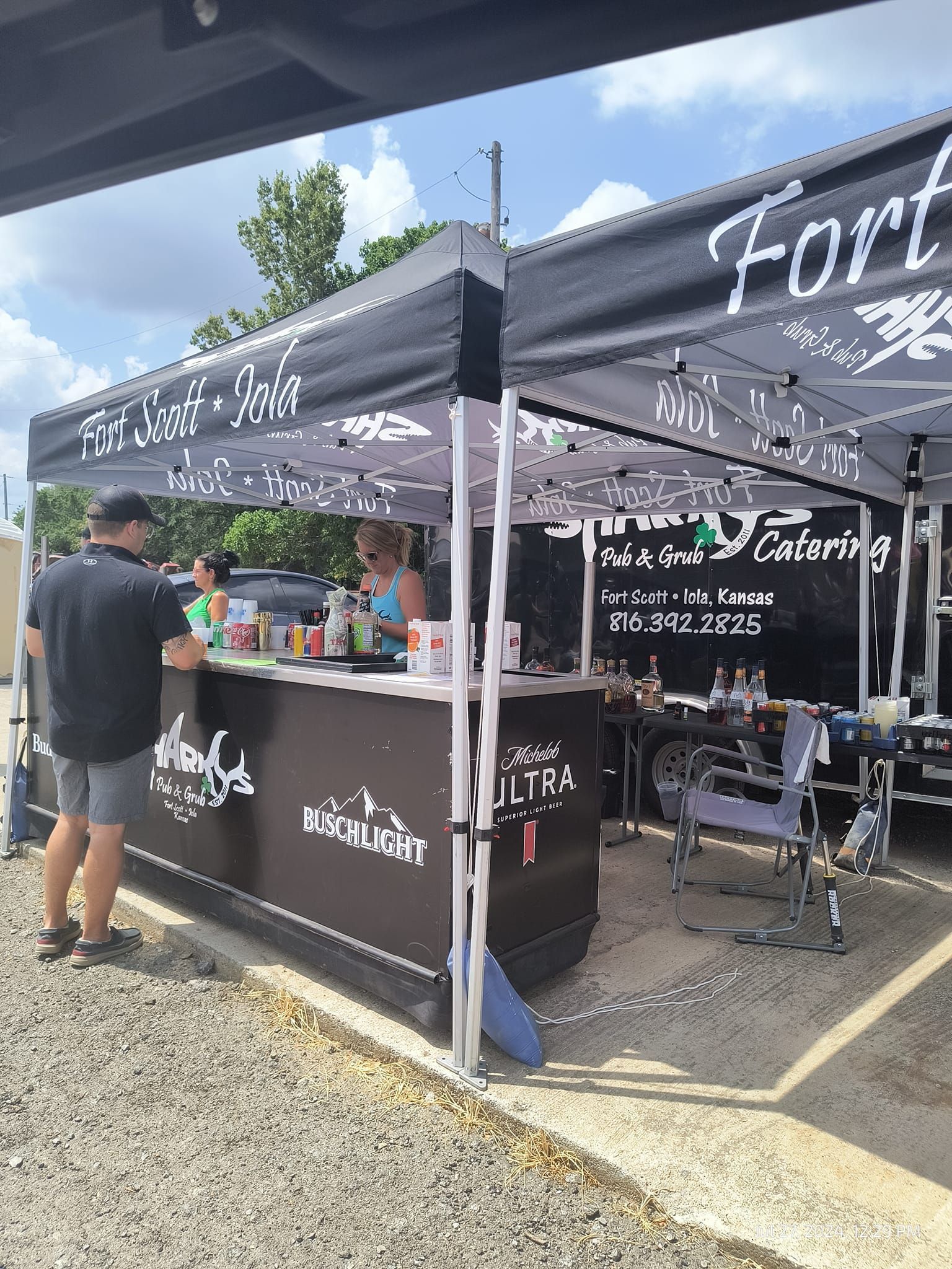 A man is standing at a bar under a tent.