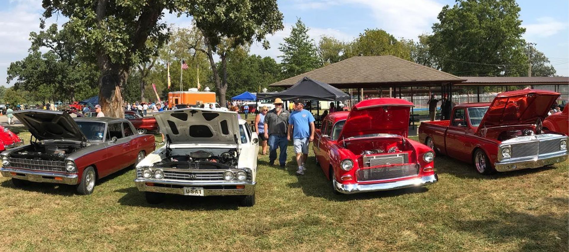 A group of cars are parked in a grassy field at a car show.