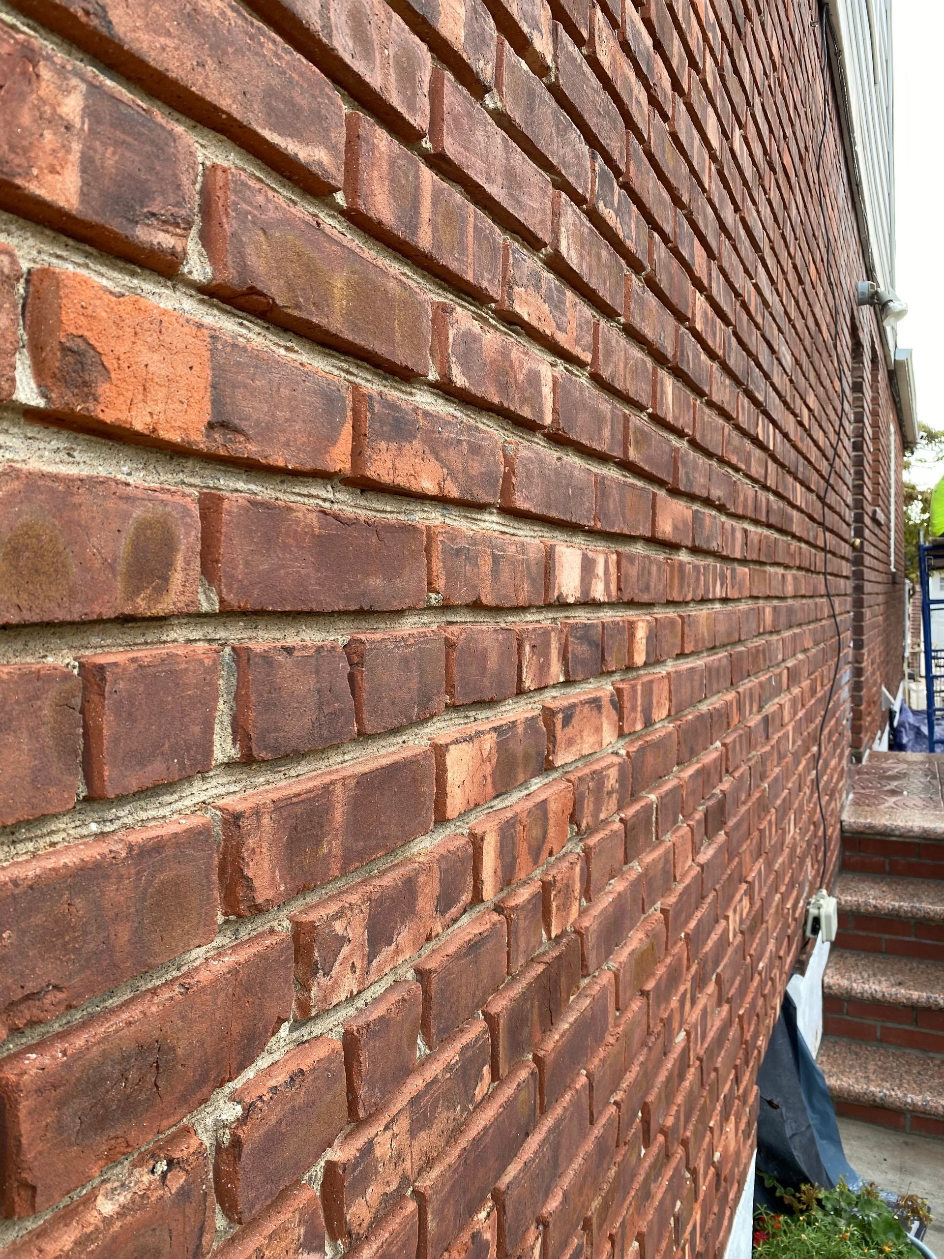 A close up of a brick wall with stairs in the background.