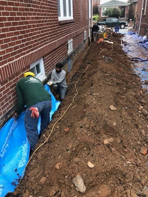 Two men are working on the side of a brick building.
