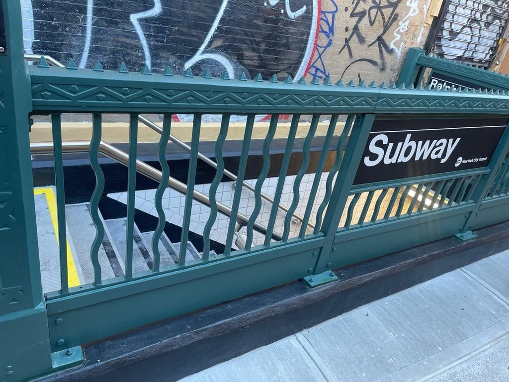 A green railing with a sign that says subway on it