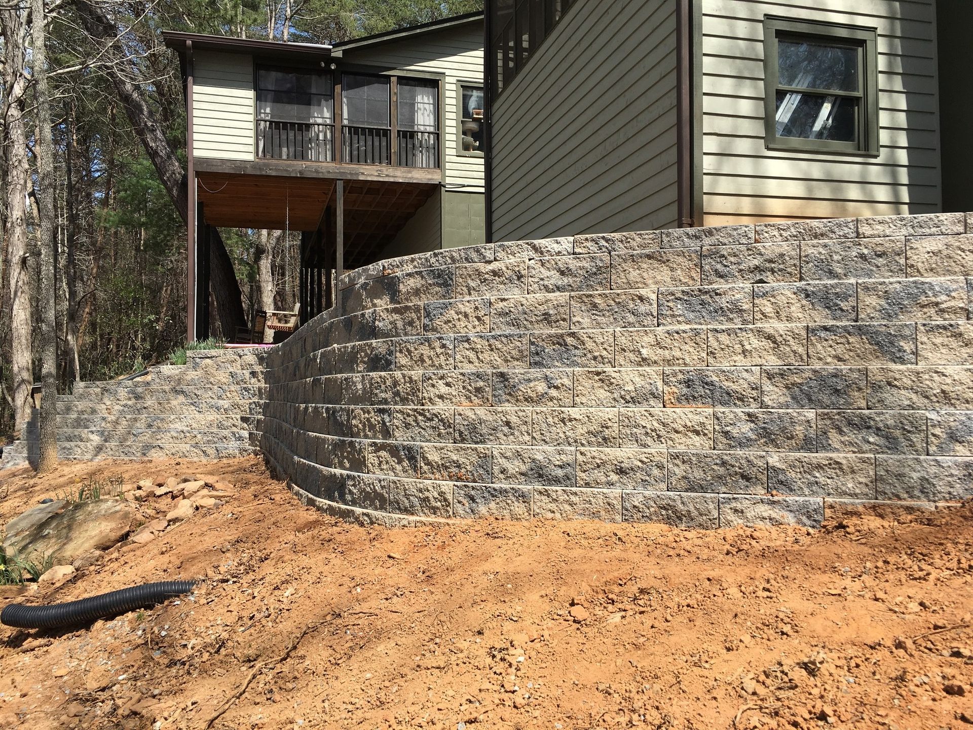 A house with a large stone wall in front of it.
