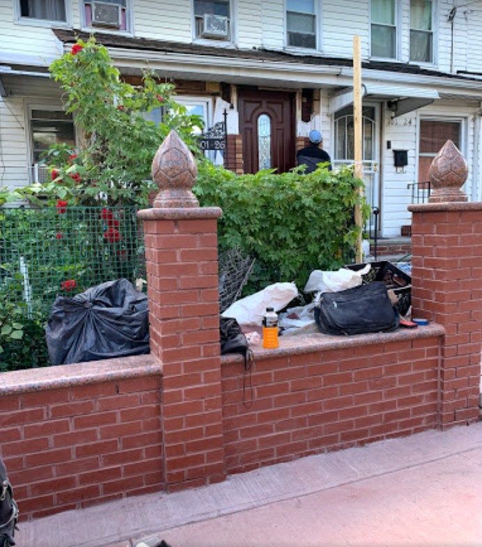 A brick wall with a lot of trash on it in front of a house.