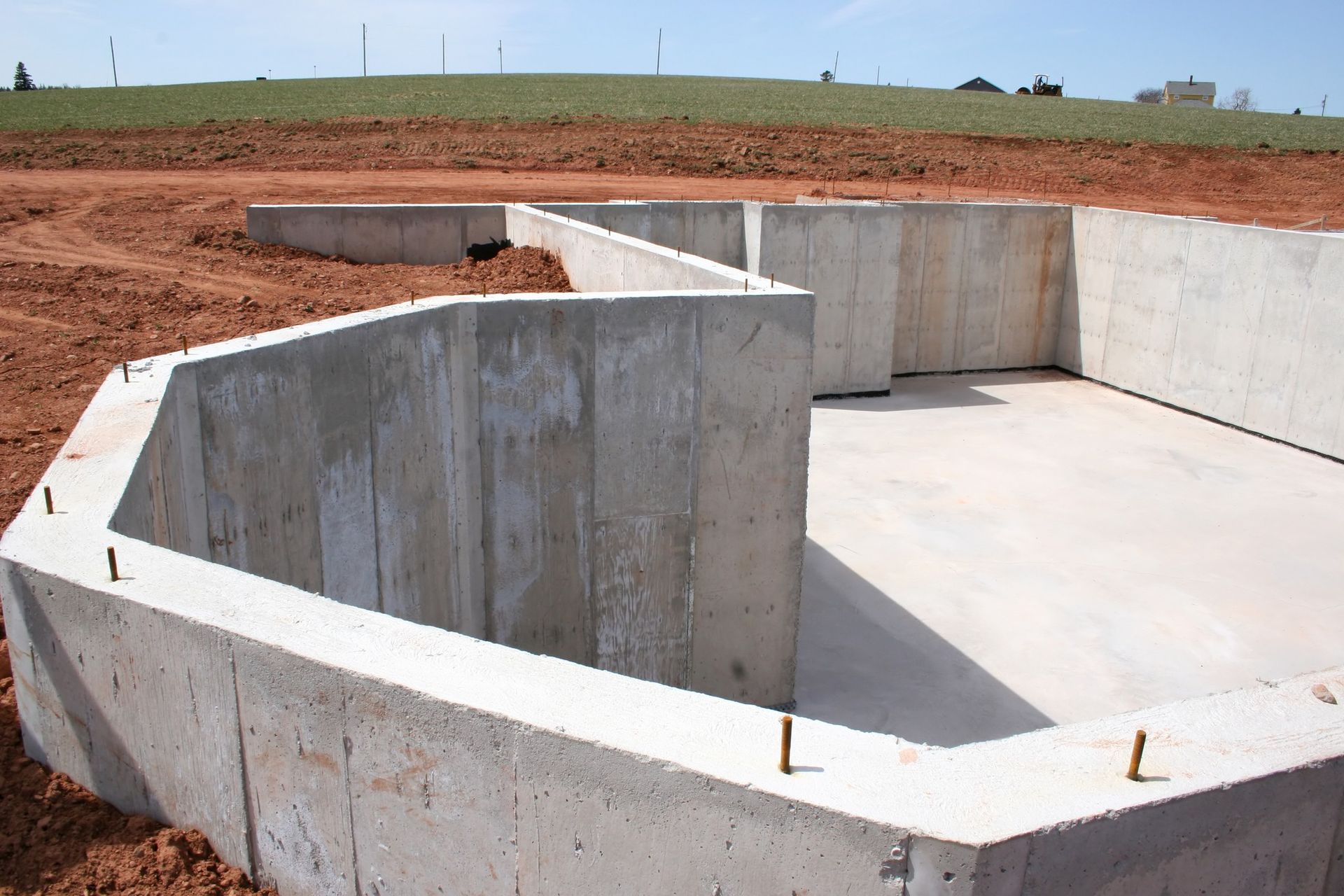 A concrete foundation is being built in a dirt field