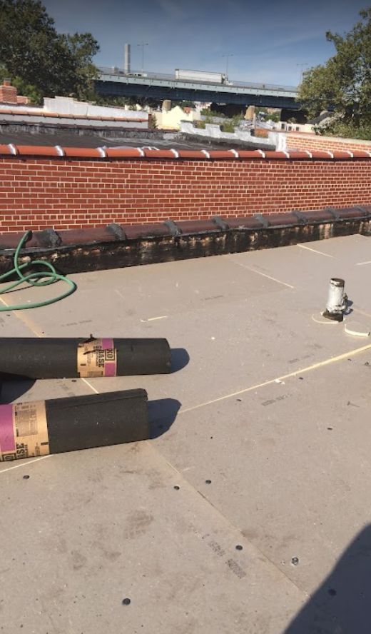 A roof with a hose on it and a brick wall in the background.