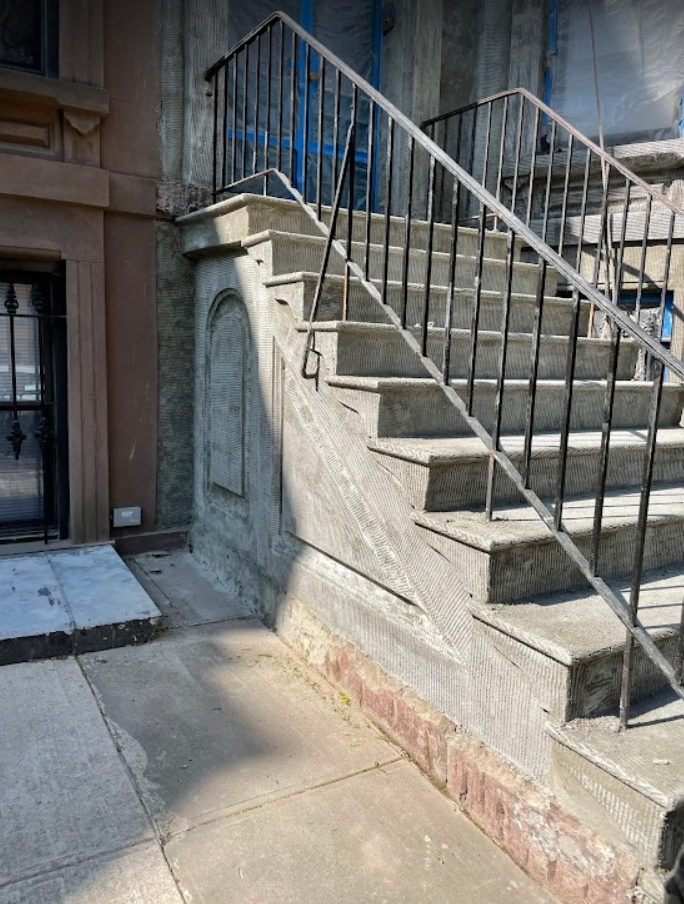 A set of stairs leading up to a building with a metal railing.