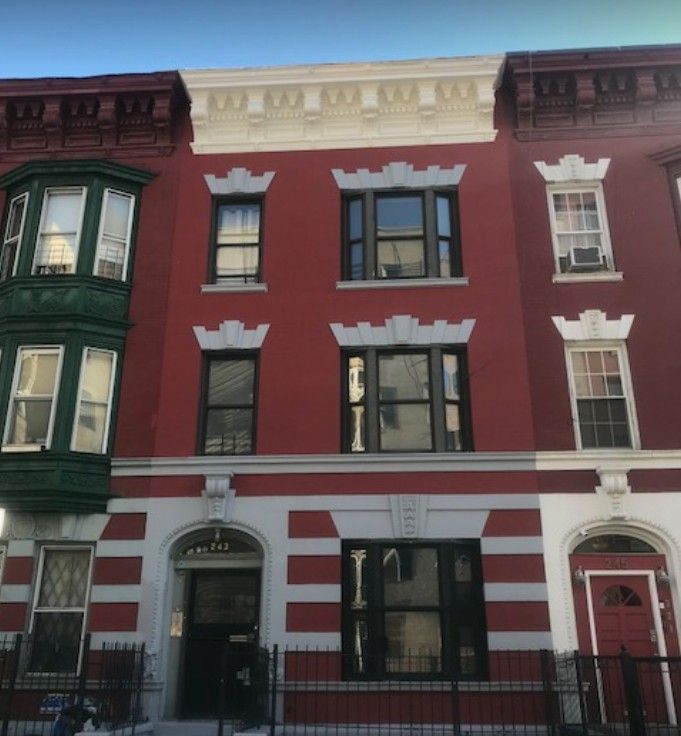 A red building with a white trim and a green bay window