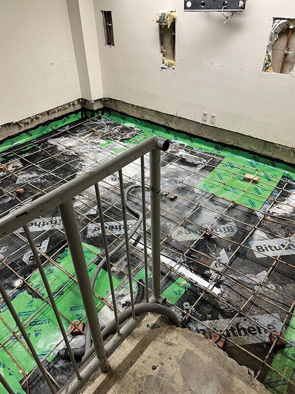 A staircase leading up to a room with a concrete floor and a metal railing.
