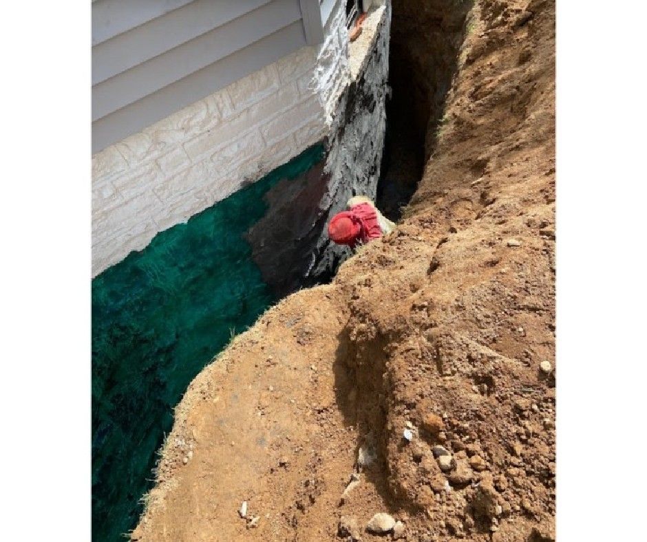 A man in a red hat is working on a foundation of a house.