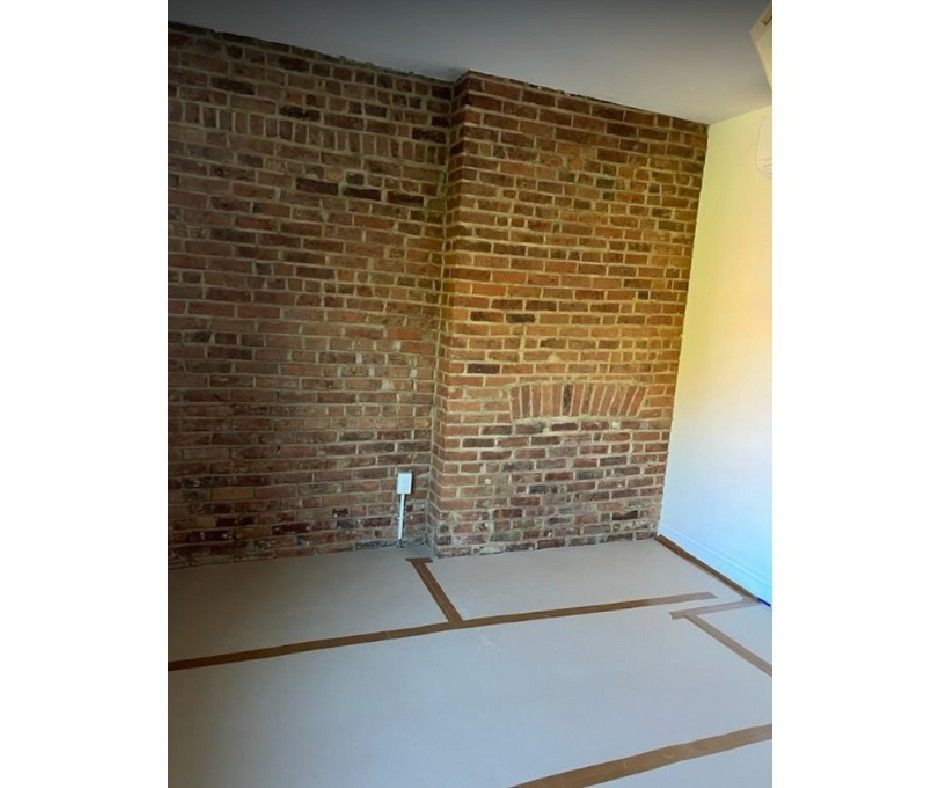 An empty room with a brick wall and a white floor.