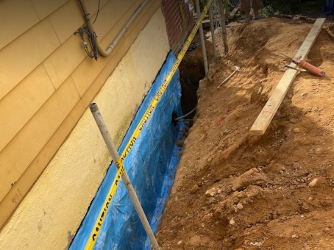 A blue tarp is covering a hole in the ground next to a house.