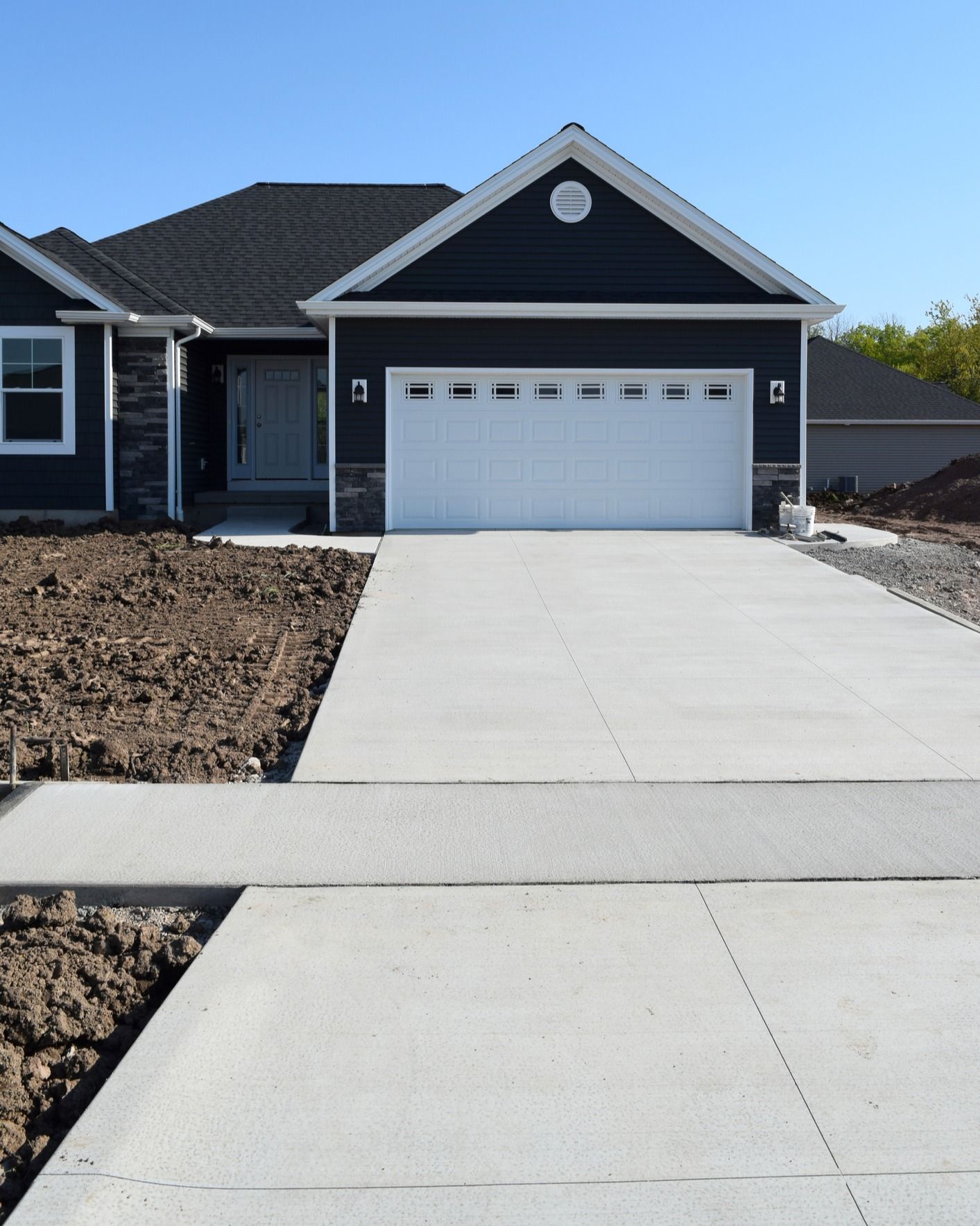 A black house with a white garage door and a concrete driveway