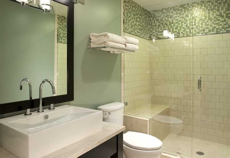 A bathroom with a sink , toilet , shower and mirror.