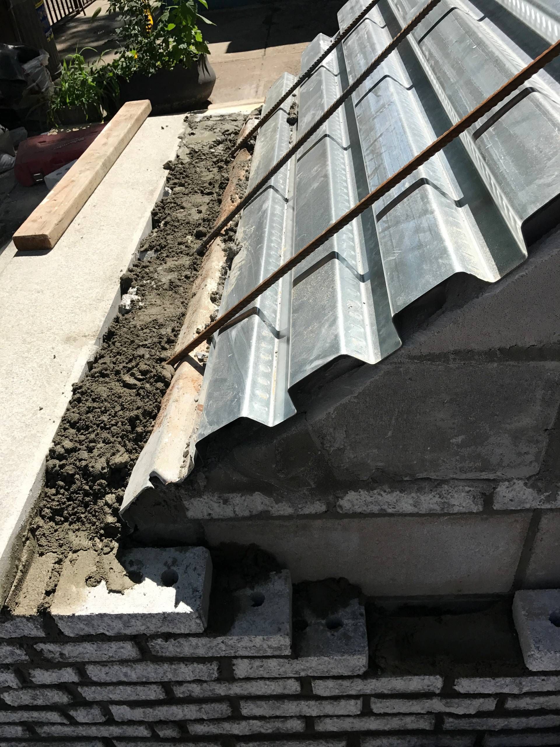 A metal roof is being built on top of a brick wall