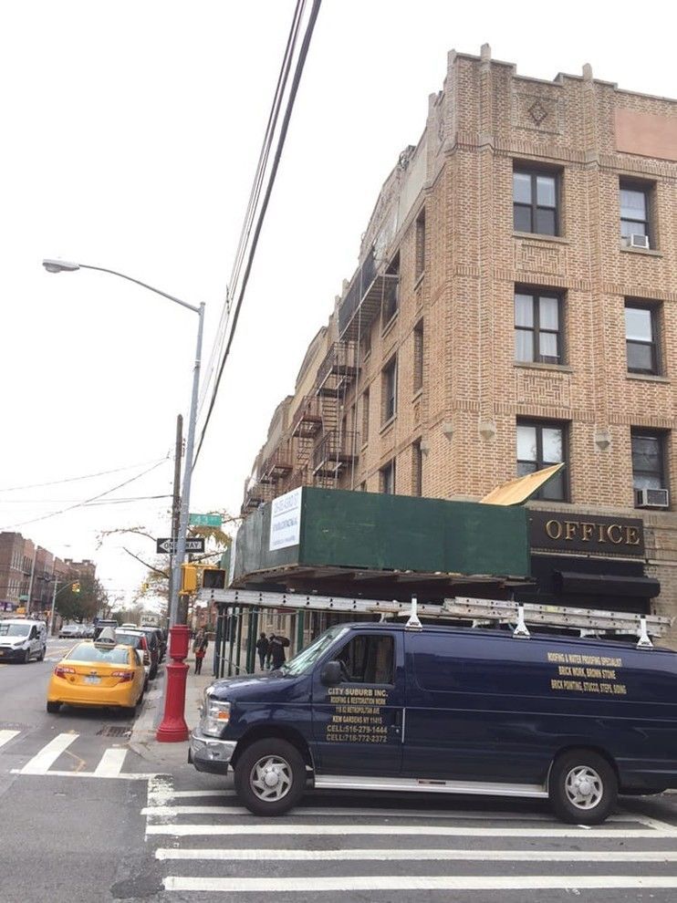 A blue van is parked in front of a building that says office