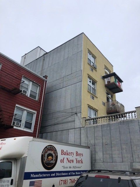 A bakery box of new york truck is parked in front of a building