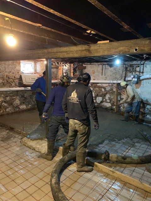 A group of men are working on a concrete floor in a basement.