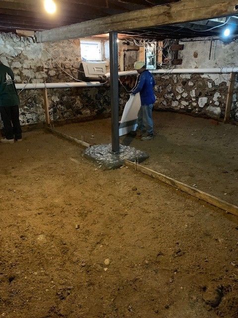 A man is carrying a bag of dirt in a basement.