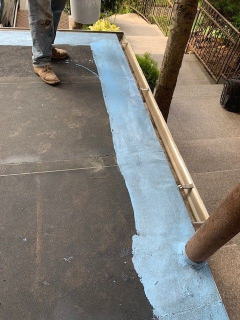 A person is standing on a roof with a blue stripe on it.