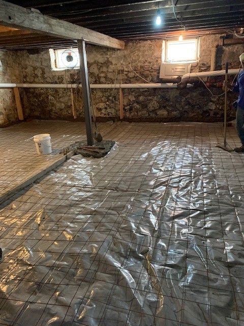 A man is standing in a basement covered in plastic.