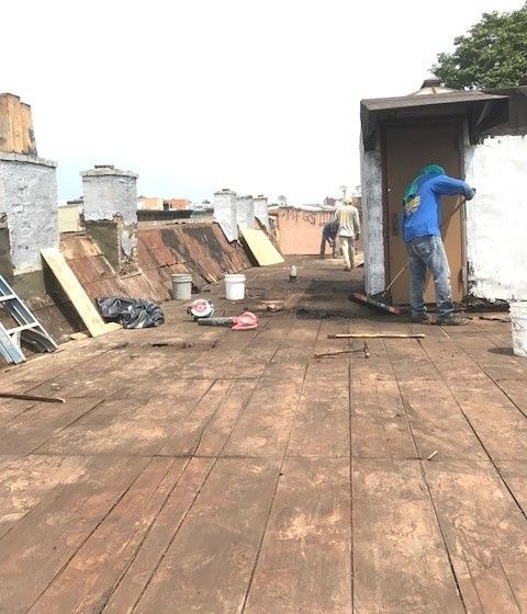 A man is sweeping the roof of a building with a broom.