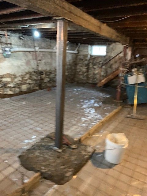 A basement with a metal pole in the middle of it.