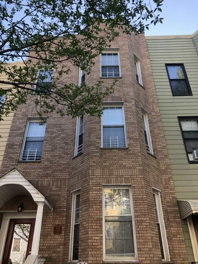 A brick building with a lot of windows and a tree in front of it.
