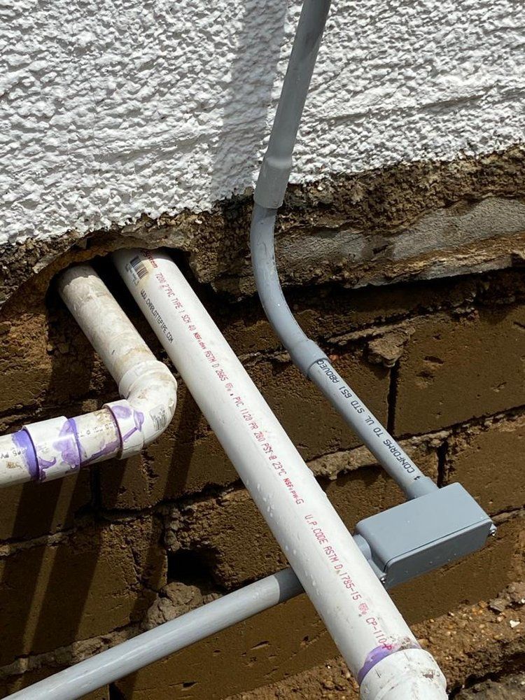 A brick wall with a bunch of pipes coming out of it