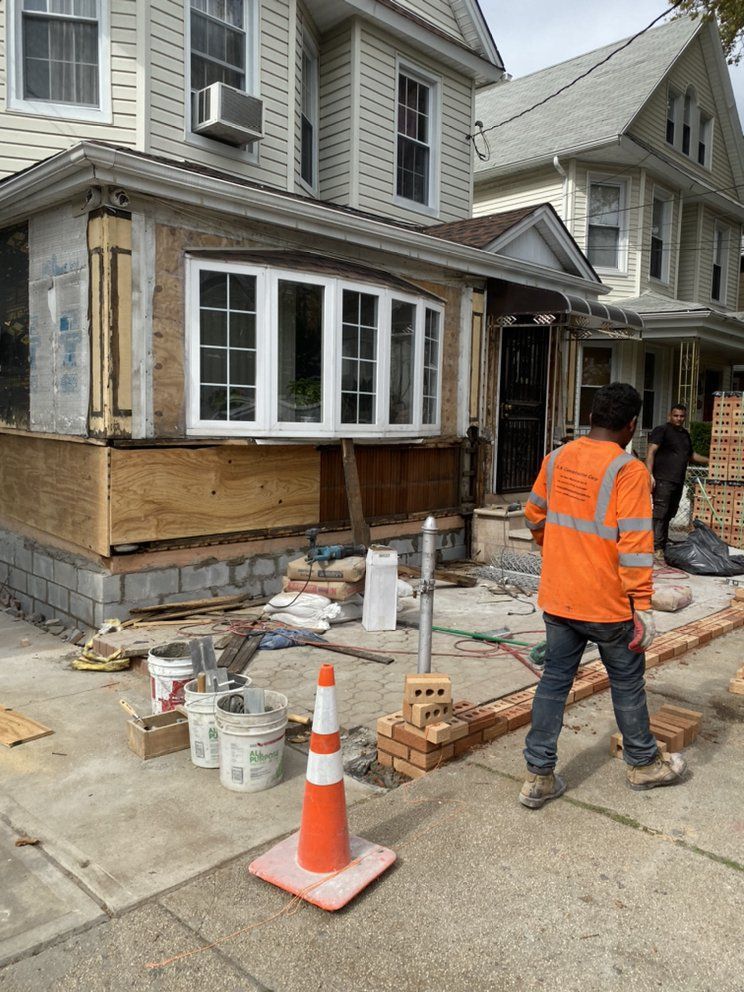 A man is standing in front of a house that is being remodeled.