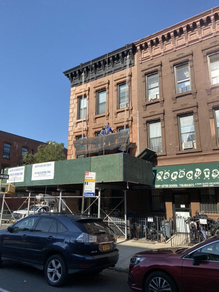 A car is parked in front of a building with a green awning that says ' scaffolding ' on it