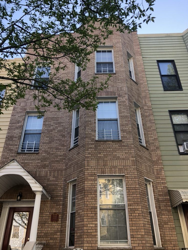 A brick building with a lot of windows and a tree in front of it.