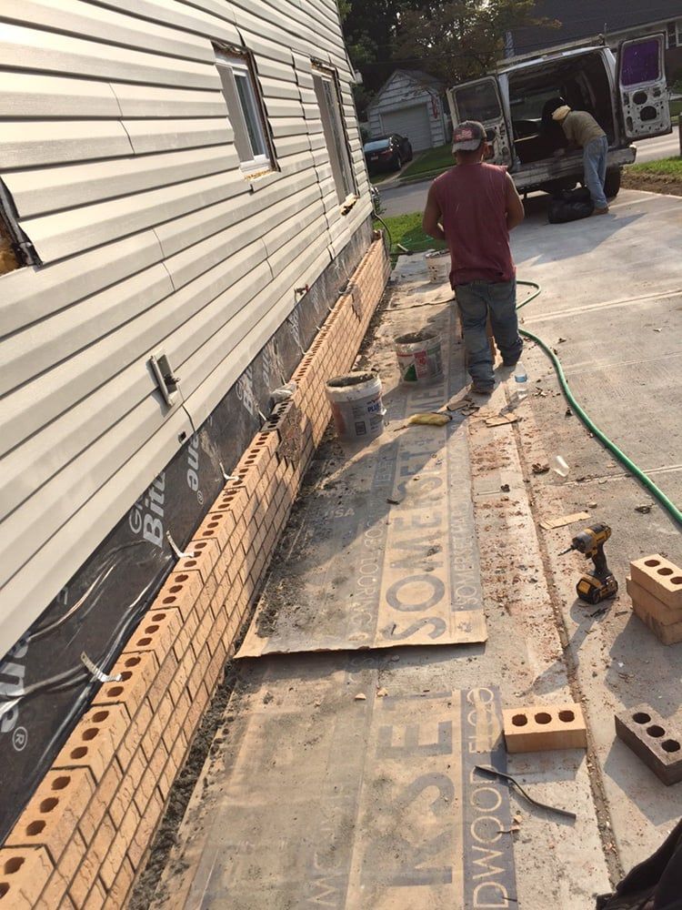 A brick wall is being built on the side of a house.