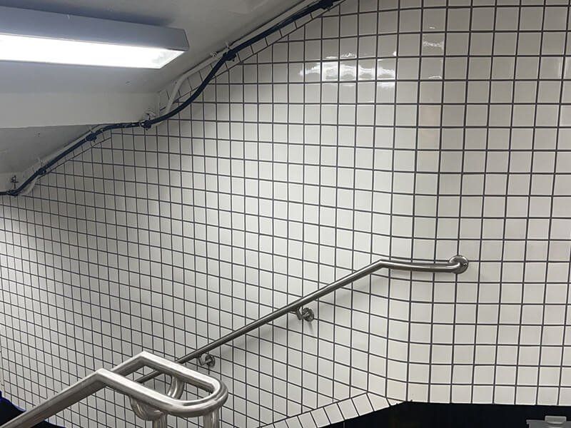 A staircase with white tiles and a metal railing