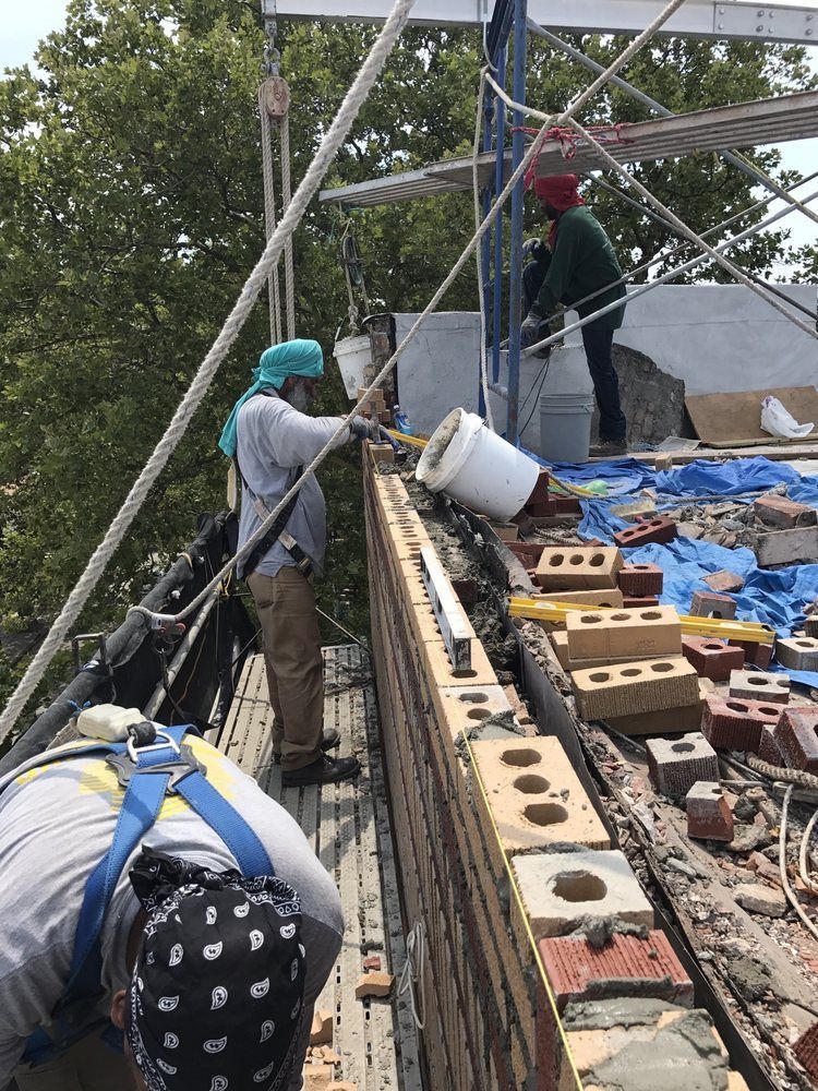 A group of construction workers are working on a brick wall.